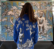 Charger l&#39;image dans la galerie, L&#39;artiste Kouka devant son mur de livres &quot;Molitor, Vibrations Artistiques&quot; réalisé sur le musée d&#39;art flottant &quot;Flucutart&quot; le dimanche 27 mars 2022.

